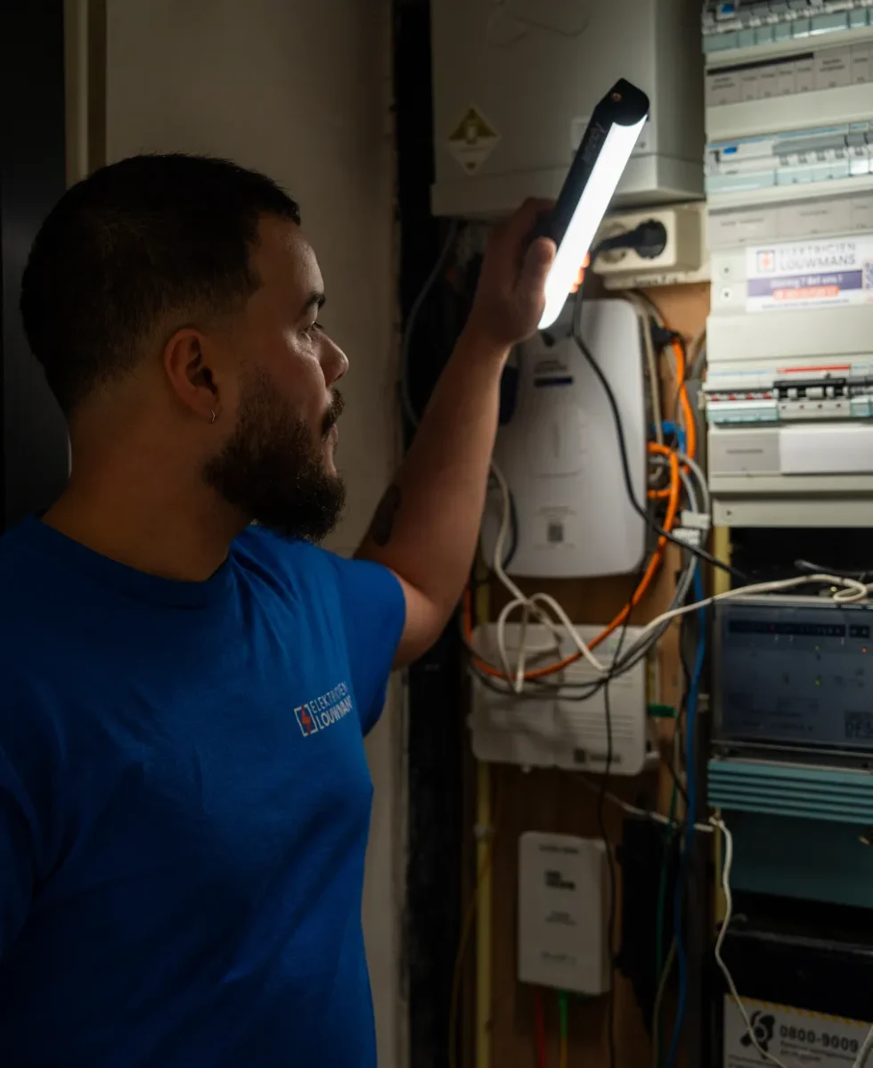 Elektricien zoekt met een lamp naar een storing in de meterkast